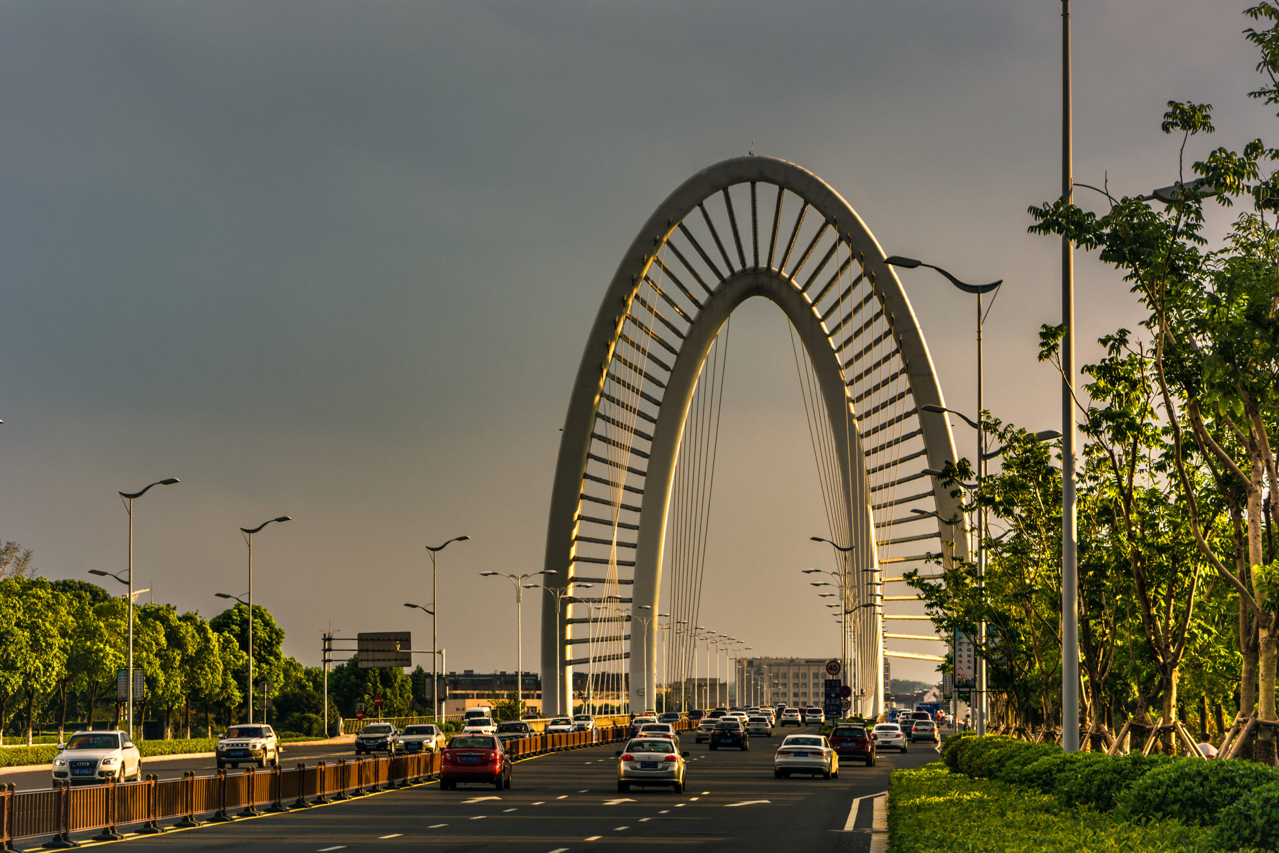 Modern arch bridge at sunset with light traffic, perfect for sightseeing via car rental with driver services.